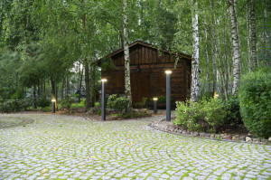 Druga część ogrodu, zaprojektowana w swobodniejszym angielskim stylu. Znajduje się tam kilka drewnianych obiektów – letni domek pełniący rolę lokum dla gości, drewutnia i duża altana. Foto. Materiały Prasowe Firmy