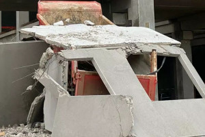 Traktor przywalony prefabrykatami na budowie
